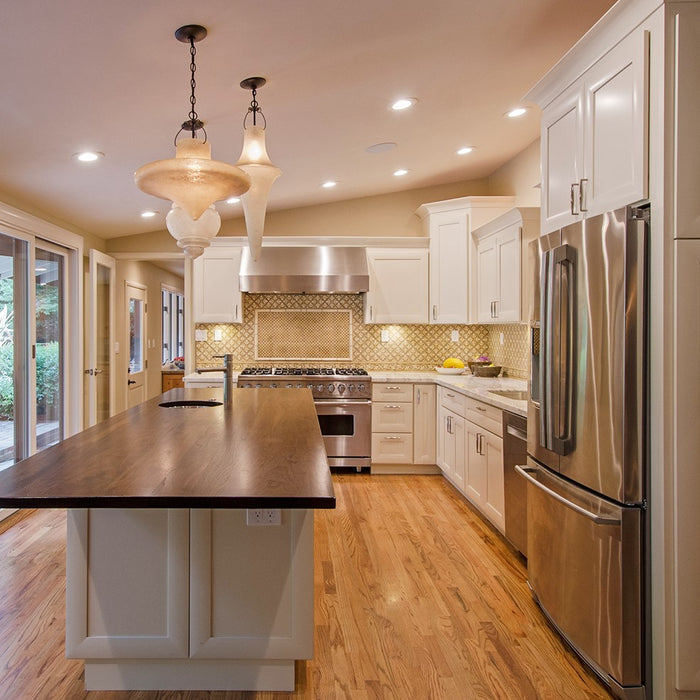 Remodeled Kitchen with White Painted Cabinets, Wood Countertop, Marble Countertop, Elaborate Backsplash and Assymetrical Pendant Lights