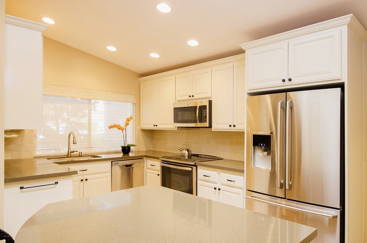 After Photo of Remodeled Kitchen with White Painted Cabinets, Stainless Steel Appliances and Quartz Countertops
